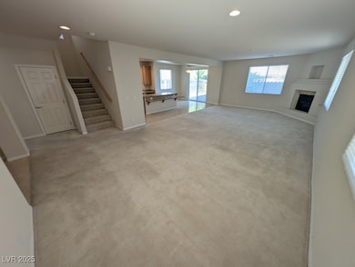 Unfurnished living room featuring recessed lighting, a glass covered fireplace, light carpet, and stairway