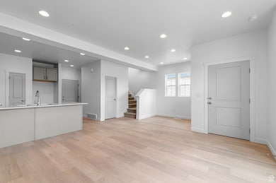 Unfurnished living room featuring recessed lighting, stairs, and light wood finished floors