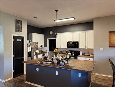 Cozy kitchen featuring a center island, dual sinks, and ample countertop space. Includes a pantry closet and a doorway leading to the laundry room and garage.