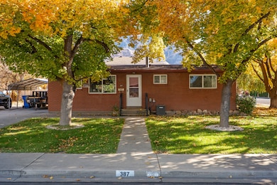 View of front facade featuring a front lawn, brick siding, and a detached carport
