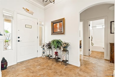 Foyer with arched walkways, baseboards, and crown
