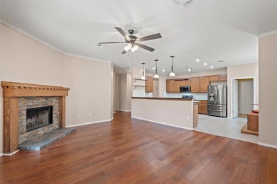 Unfurnished living room featuring light wood finished floors, crown molding, a ceiling fan, a stone fireplace, and recessed lighting