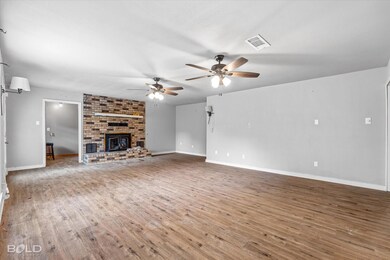 Unfurnished living room featuring brick wall, a fi