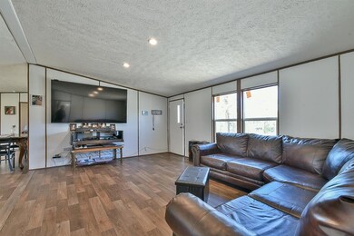 Living area featuring wood finished floors, a textured ceiling, lofted ceiling, and recessed lighting