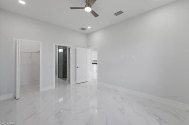 Unfurnished bedroom with light marble finish floors, a walk in closet, recessed lighting, and a ceiling fan