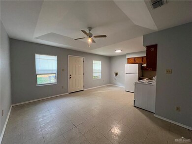 Unfurnished living room featuring ceiling fan, a tray ceiling, and light flooring