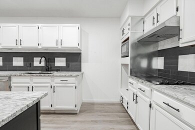 Kitchen with white cabinets, tasteful backsplash, 