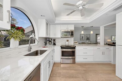 Kitchen with sink, decorative backsplash, a tray ceiling, white cabinetry, and stainless steel appliances