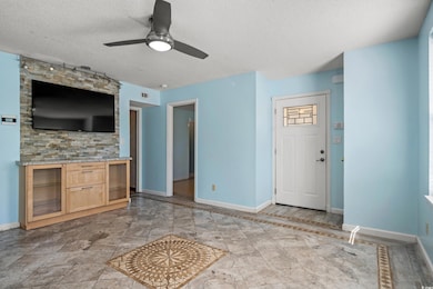 Unfurnished living room featuring a textured ceiling and a ceiling fan