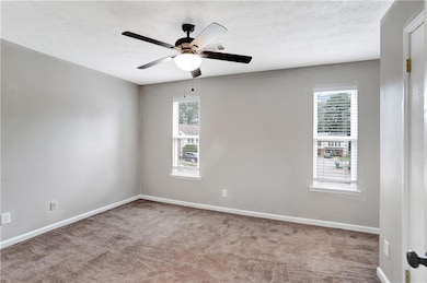 Spare room featuring carpet flooring, a ceiling fan, and a textured ceiling