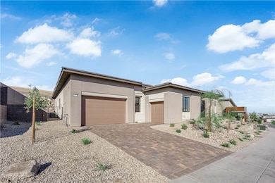 Prairie-style home featuring stucco siding, decorative driveway, and a garage