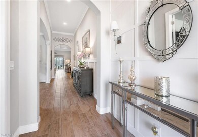 Hall with arched walkways, crown molding, light wood finished floors, and baseboards