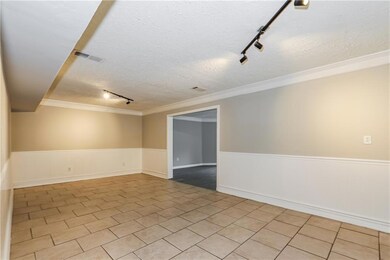 Unfurnished room featuring track lighting, a textured ceiling, wainscoting, tile patterned floors, and crown molding