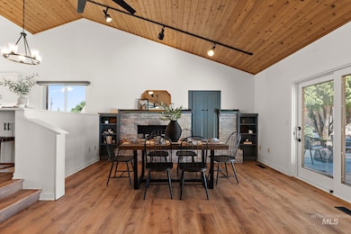 Dining space featuring track lighting, wood ceiling, high vaulted ceiling, a brick fireplace, and wood finished floors