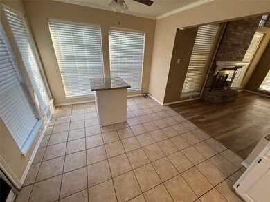 Unfurnished dining area with light tile patterned floors, a textured ceiling, crown molding, a fireplace, and a ceiling fan