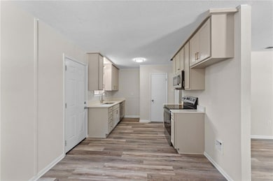 Kitchen featuring stainless steel appliances, light wood-type flooring, and a textured ceiling