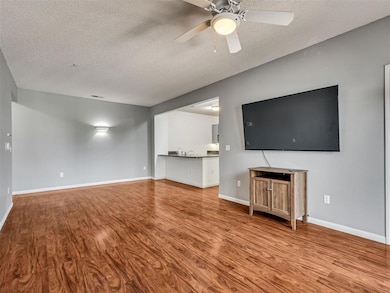 Unfurnished living room with a textured ceiling, wood finished floors, and a ceiling fan
