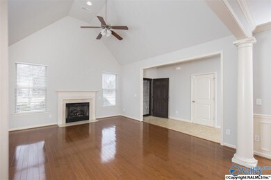 Open Living Room with a gas fireplace, mantle, marble surround, Vaulted Ceiling, hardwood floors, and ceiling fan.