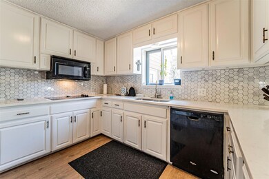The kitchen features a flat-top cooktop, built-in microwave, and plenty of counter and cabinet space. To the right is a pass-through to the sunny breakfast nook.