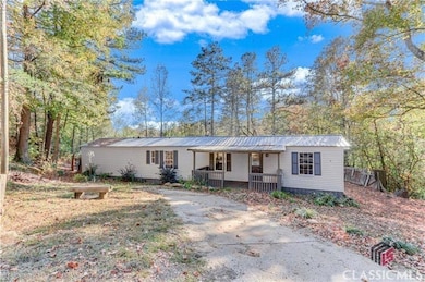 Manufactured / mobile home with a porch, a metal roof, and view of wooded area