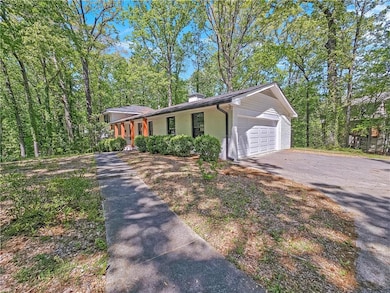 Single story home featuring driveway, a garage, a chimney, and covered porch