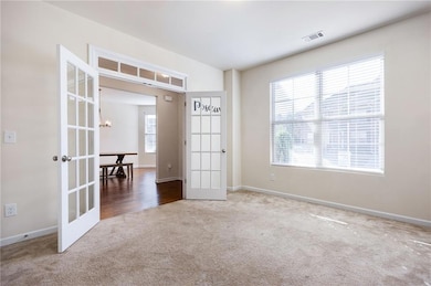Spare room with carpet, french doors, and a chandelier