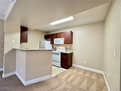 Kitchen with white appliances, baseboards, light c