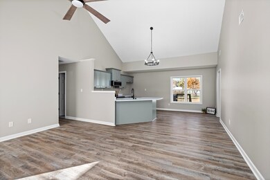 Kitchen featuring high vaulted ceiling, gray cabinets, light countertops, a chandelier, and dark wood-type flooring