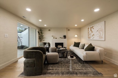 Living area with a fireplace, baseboards, wood finished floors, and recessed lighting