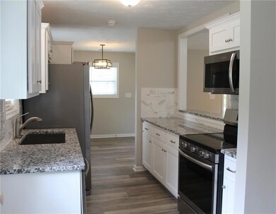 Kitchen with stainless steel appliances, a sink, white cabinets, and dark wood finished floors