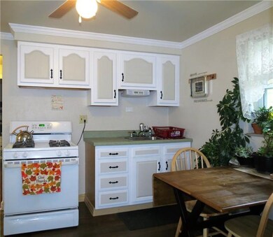 FULLY EQUIPPED EAT IN KITCHEN FEATURES A GAS STOVE, REFRIGERATOR AND CEILING FAN.