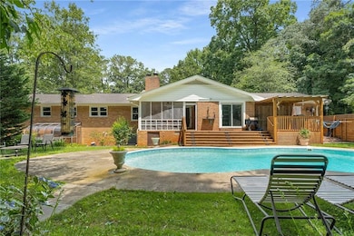 Outdoor pool with a sunroom, a deck, and a patio area