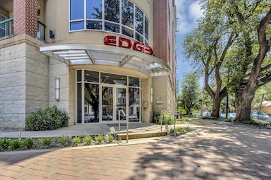 The building entrance features modern architecture and beautiful landscaping.
