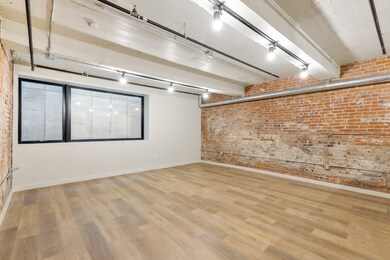 Spare room with brick wall, track lighting, and light hardwood / wood-style floors