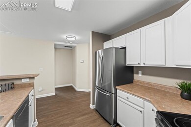 Kitchen with white cabinetry, baseboards, appliances with stainless steel finishes, and dark wood finished floors