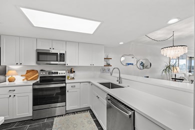 Kitchen featuring appliances with stainless steel finishes, white cabinetry, recessed lighting, a skylight, and open shelves