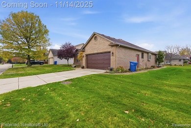View of side of home with driveway, a lawn, brick siding, and an attached garage