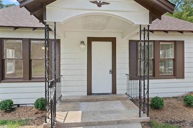 Entrance to property with roof with shingles and a porch