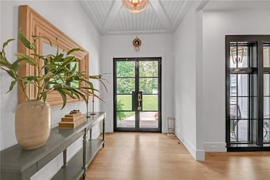 Doorway to outside with french doors, light wood-type flooring, shiplap ceiling, baseboards.