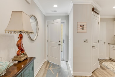 Entryway featuring light wood-style flooring, ornamental molding, baseboards, and recessed lighting