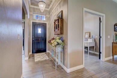 Tiled entrance foyer featuring crown molding and an inviting chandelier