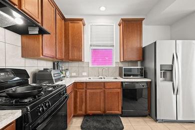 Kitchen featuring black appliances, brown cabinetry, and under cabinet range hood