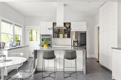 Kitchen featuring modern cabinets, a breakfast bar area, white cabinets, appliances with stainless steel finishes, and a kitchen island