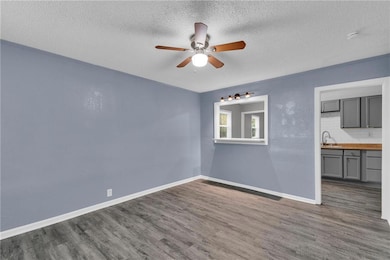 Spare room featuring dark wood finished floors, a textured ceiling, and ceiling fan