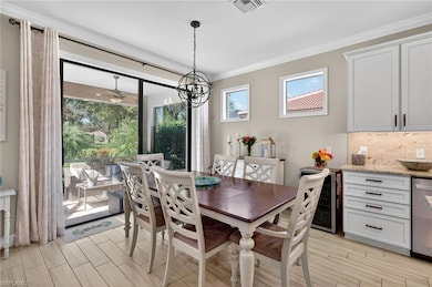 Dining area featuring wood finish floors, ornamental molding, beverage cooler, and a chandelier