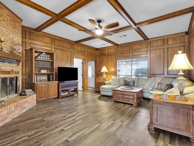 Living room featuring a fireplace, wood walls, dark hardwood / wood-style flooring, coffered ceiling, and beam ceiling