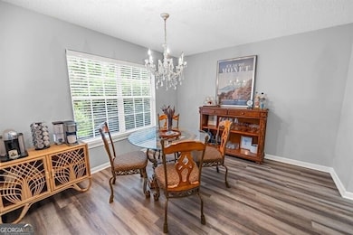 Dining room with a chandelier, wood finished floors, baseboards, and a textured ceiling