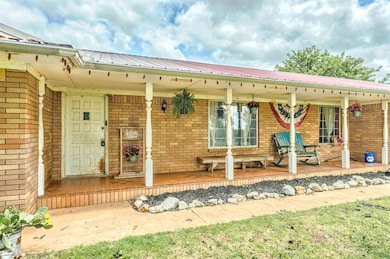 Property entrance with brick siding, covered porch, and a metal roof