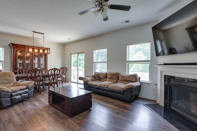 Living area featuring dark wood-style flooring, a premium fireplace, and ceiling fan