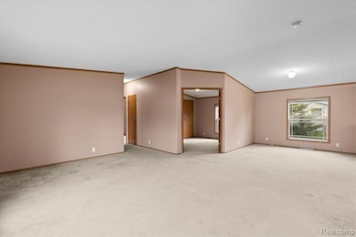 Spare room featuring crown molding and light colored carpet